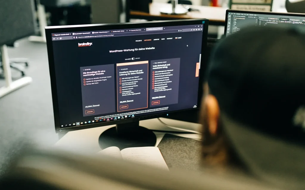 Website Wartung mit Tim Haag der auf einen Monitor mit Wartungspaketen schaut